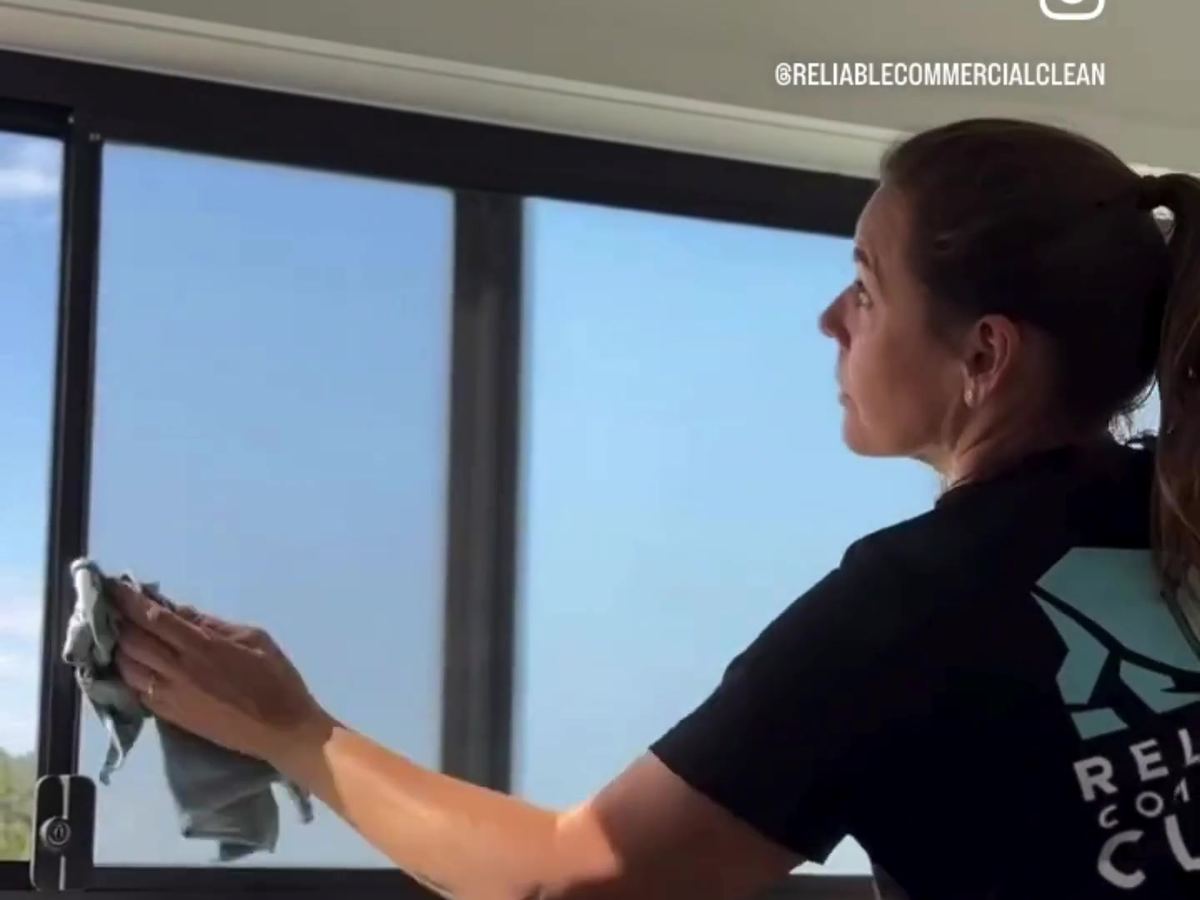 Cleaner wiping office windows streak-free on the Sunshine Coast